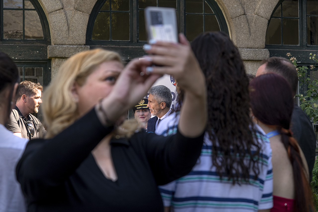 Una asistente se hace un selfie con el ministro del Interior al fondo